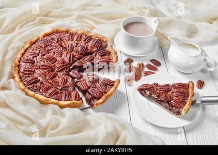 torta pecan affettata su un piatto bianco servito con latte caldo al cioccolato, vista orizzontale dall'alto, primo piano Foto Stock