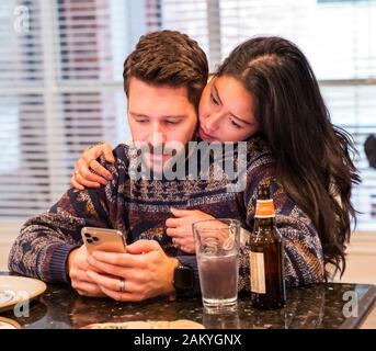 Affettuosa giovane coppia sposata guardando uno smart phone Foto Stock