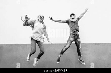 Felice pazzo coppia senior saltando insieme all'aperto - maturo persone alla moda che hanno divertimento celebrare e ballare fuori Foto Stock