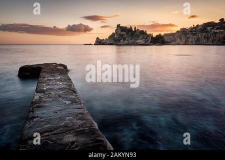 Molo roccioso che indica la direzione della bellissima isola (Isola Bella), Taormina, Sicilia, Italia Foto Stock