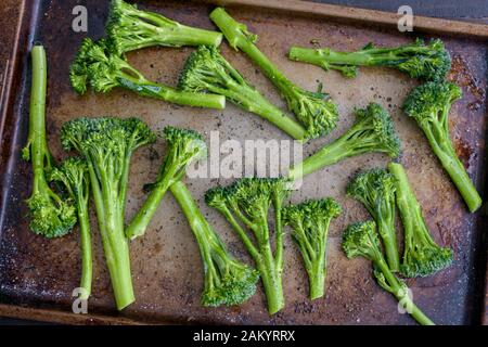 Broccolini crudi Conditi con olio di oliva su una vaschetta: Broccolini crudi fatti insaporire con olio di oliva e conditi con sale e pepe Foto Stock