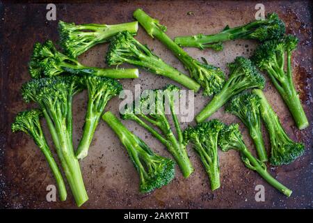 Broccolini crudi Conditi con olio di oliva su una vaschetta: Broccolini crudi fatti insaporire con olio di oliva e conditi con sale e pepe Foto Stock