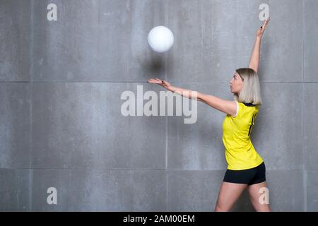 Donna giovane giocatore di volleyball su sfondo grigio Foto Stock