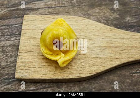 Particolare dei tortellini crudi, pasta tradizionale italiana. Sfondo in legno Foto Stock