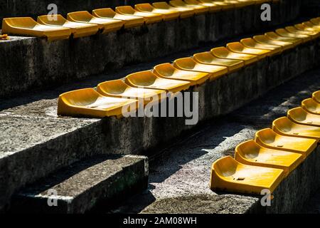 Usato piccole sedie gialle in plastica su un piccolo stadio. Foto Stock