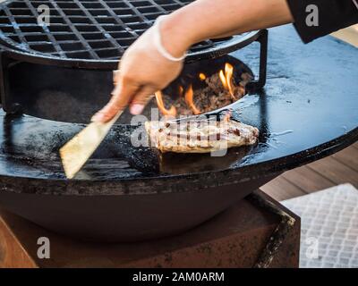 Cook prepara le costolette su griglia circolare a Sochi Foto Stock