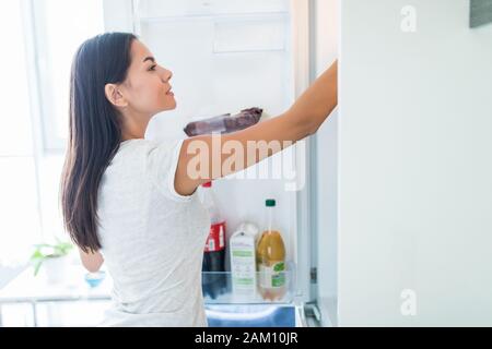 Mangiare sano concetto .dieta. Bella giovane donna vicino al frigorifero con alimenti sani. Frutta e verdura in un frigo Foto Stock