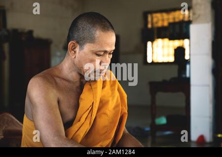 Sangkat Krabei Riel, Provincia di Siem Reap, Cambogia - 4 Aprile 2013: Monaco buddista cambogiano con tela arancione che guarda giù il tempio Wat Krabi Riel Pago Foto Stock