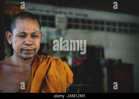 Sangkat Krabei Riel, Provincia di Siem Reap, Cambogia - 4 Aprile 2013: Monaco buddista cambogiano con tela arancione e immagini sullo sfondo al tempio Wat Kra Foto Stock