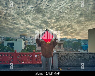 Jaipur, Rajasthan circa 2020 - Fotografia di un uomo che tiene un aquilone sopra la sua testa sul tetto di una casa. La fotografia è scattata in un bellissimo inverno Foto Stock