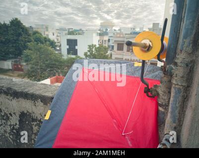 Jaipur, Rajasthan , circa 2020 - Fotografia di una bobina colorata di filo, charkhi e manjha, su un aquilone rosso brillante con filetto bianco in esecuzione Foto Stock