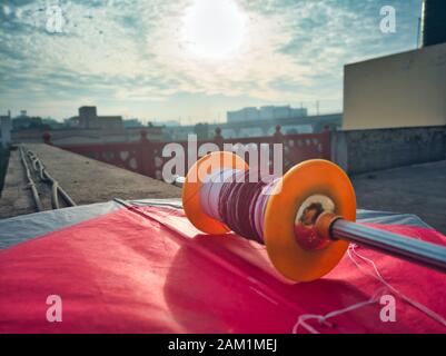 Jaipur, Rajasthan , circa 2020 - Fotografia di una bobina colorata di filo, charkhi e manjha, su un aquilone rosso brillante con filetto bianco in esecuzione Foto Stock