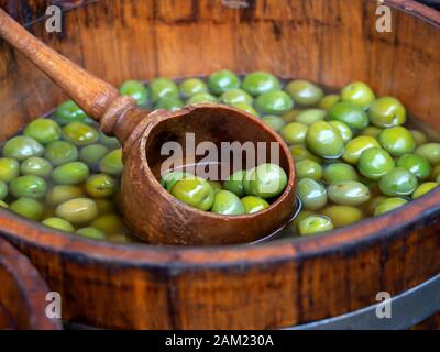 Barile di legno di Olive verdi con siviera a un mercato alimentare Foto Stock