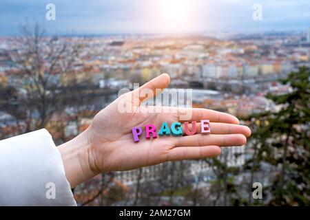 La parola Praga di lettere colorate sul palmo di un turista sullo sfondo della città di Praga nella Repubblica Ceca Foto Stock