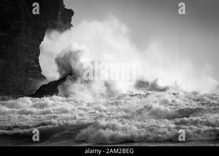 Immagine in bianco e nero di grandi onde che si infrangono contro le rocce di Piha Beach, Waitakere, Nuova Zelanda Foto Stock