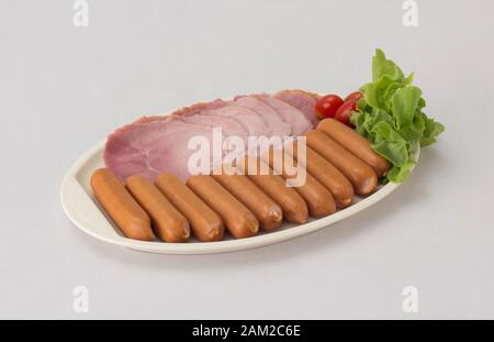 Salsicce affumicate e prosciutto affettato servito con pomodoro e verdure su piatto bianco isolato su sfondo bianco Foto Stock