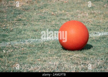 Un campo da gioco rosso si trova accanto alla linea bianca su un campo verde erba. Aspetto antico o invecchiato. Foto Stock