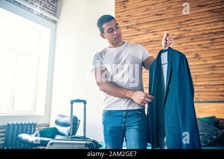 Dai capelli scuri giovane uomo in bianco tshirt hoding una camicia Foto Stock