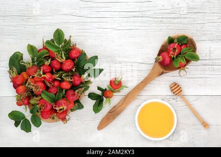 Rosehip frutti di bosco cibo salute usato in medicina a base di erbe per il freddo e l'influenza rimedio bere con miele. Superfood molto alto in antiossidanti e vitamina c. Foto Stock