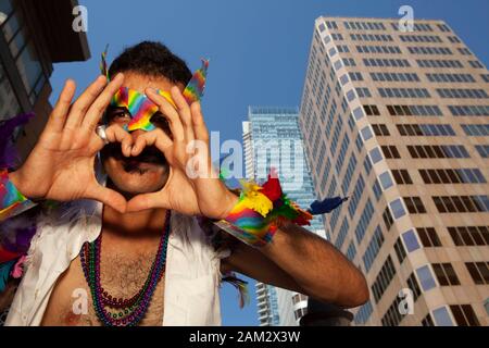 Vista ad angolo basso del partecipante alla parata Pride, simbolo a forma di cuore, edifici alti sullo sfondo, Vancouver Pride Festival 2014, Vancouver, Canada Foto Stock