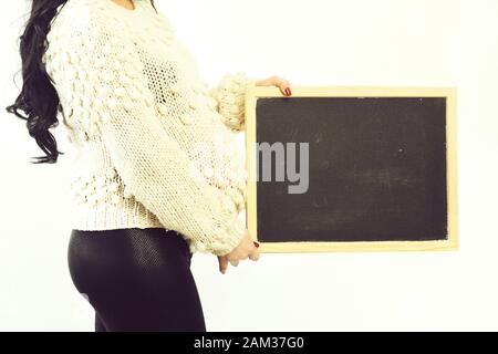 mani femminili di donna incinta che tiene bordo nero maglione di maglia inbeige isolato su sfondo bianco studio, spazio di copia Foto Stock