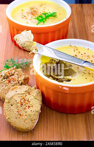 Pato fatto in casa di fegato di pollo con burro in ramekin, su legno. Baguette con pate. Foto Stock