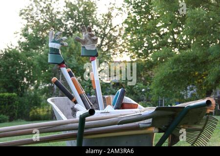 Carriola con guanti da giardinaggio su attrezzi in serata sole atmosferica primo piano Foto Stock