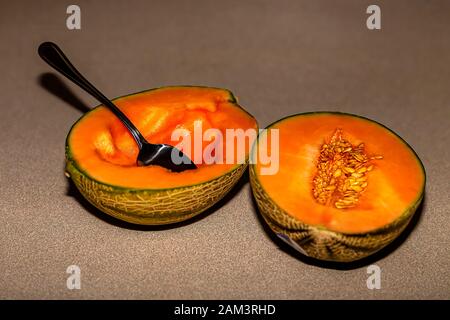 La metà del melone Charentais nordamericano con il cucchiaio da pranzo. Il melone Charentais è una piccola varietà di melone. Foto Stock