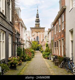 Città Vecchia, Haarlem, Paesi Bassi. Una tipica strada laterale acciottolata a Haarlem, Olanda, con la Grote Kerk (Grande Chiesa) in lontananza. Foto Stock