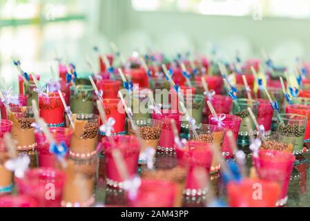 Primo piano di tazze trasparenti con cucchiaio di cioccolato e plastica con arco blu sulla festa dei bambini. Messa a fuoco selettiva. Foto Stock