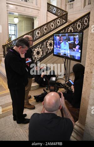 I giornalisti di guardare un feed dal vivo su una televisione che mostra la elezione di altoparlanti all'Assemblea dell'Irlanda del Nord presso gli edifici del Parlamento europeo, Stormont, Belfast, Irlanda del Nord, come la condivisione di potenza complessivo in Irlanda del Nord è stato ripristinato. Foto Stock