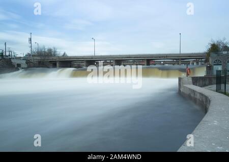 Una lunga esposizione di acqua che passa sopra una diga a Fenelon Falls, Su. Foto Stock