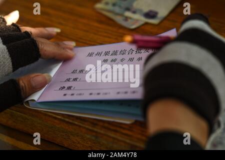 (200111) -- SANYA, 11 genn. 2020 (Xinhua) -- Un personale scrive una registrazione ricevuta il peso del carico a tutta una vendita sul mercato della frutta e della verdura nel quartiere Yazhou di Sanya, Cina del sud della provincia di Hainan, 8 gennaio, 2020. Yazhou District è un importante hub di produzione vegetale in provincia di Hainan. (Foto di Pu Xiaoxu/Xinhua) Foto Stock