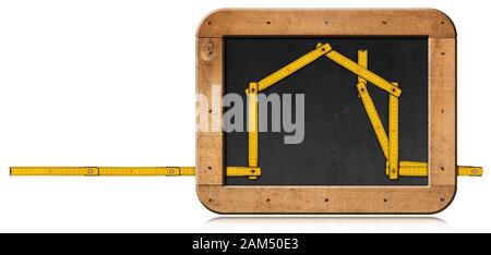 Righello pieghevole in legno giallo nella forma di una casa in una lavagna con spazio copia. Isolato su sfondo bianco Foto Stock