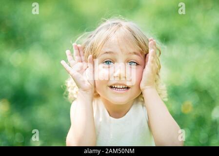 ragazza sniffing fiori di mela frutteto. giardino con alberi in fiore. Stagione delle allergie. Bambino che riposa in giardino fiorito in primavera. Foto Stock