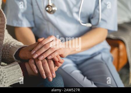 Chiusura del giovane medico che seduto vicino al paziente Foto Stock