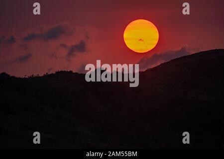 Tramonto su Whitsunday Island, Queensland con colori esagerati dal fumo dai vicini fuochi d'imboscata Foto Stock