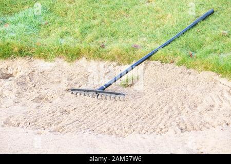 Il rastrello nel bunker di sabbia a golf links corso verde per i golfisti Foto Stock