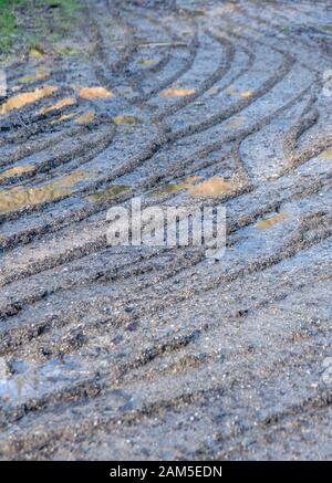 Per impieghi pesanti tracce di pneumatici nel campo fangoso. Metafora impantanarsi, di stagione inverno meteo. Curve di astratto, curvo tracce del veicolo. Foto Stock