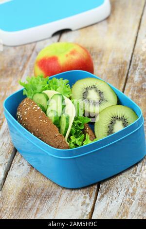 Pranzo al sacco sano contenente rotolo di formaggio di segale, kiwi e mela rossa Foto Stock