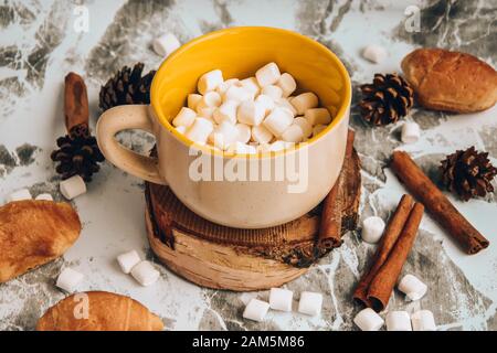 Una tazza di cioccolato caldo e cacao di Natale Capodanno delizioso con marshmallow cosparso di polvere di cacao, coni e croissant, cannella su un grigio Foto Stock