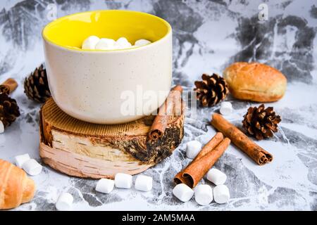 Una tazza di cioccolato caldo e cacao di Natale Capodanno delizioso con marshmallow cosparso di polvere di cacao, coni e croissant, cannella su un grigio Foto Stock