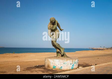 Statua in pietra di un corridore in piedi sulla riva del mare. E' una bella spiaggia lunga Foto Stock