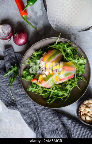 Spuntino a basso contenuto calorico, peperone, tofu affumicato e rotoli di carta di riso a cipolla rossa serviti con rucola fresca e pistacchi Foto Stock