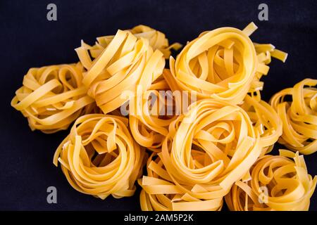 Pasta all'uovo, Tagliatelle Pasta, sfere rotonde di pasta cruda su fondo nero Foto Stock