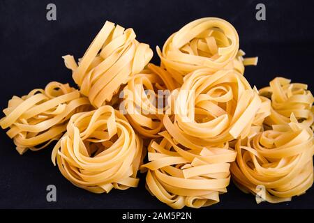 Pasta all'uovo, Tagliatelle Pasta, sfere rotonde di pasta cruda su fondo nero Foto Stock