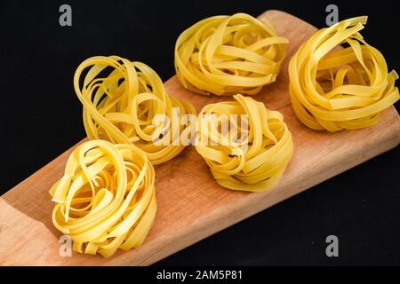 Pasta all'uovo, Tagliatelle Pasta, sfere rotonde di pasta cruda su fondo nero Foto Stock