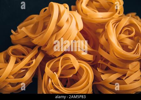 Pasta all'uovo, Tagliatelle Pasta, sfere rotonde di pasta cruda su fondo nero Foto Stock