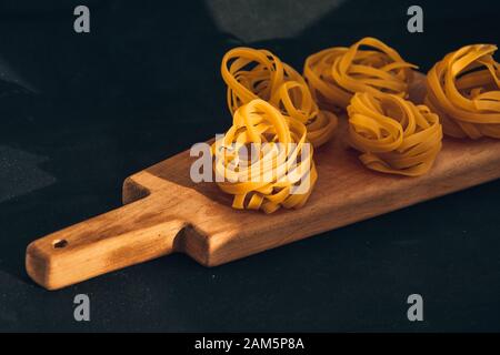 Pasta all'uovo, Tagliatelle Pasta, sfere rotonde di pasta cruda su fondo nero Foto Stock