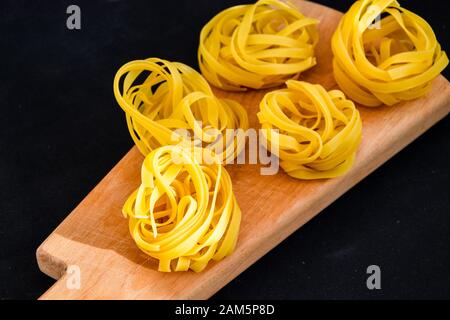 Pasta all'uovo, Tagliatelle Pasta, sfere rotonde di pasta cruda su fondo nero Foto Stock